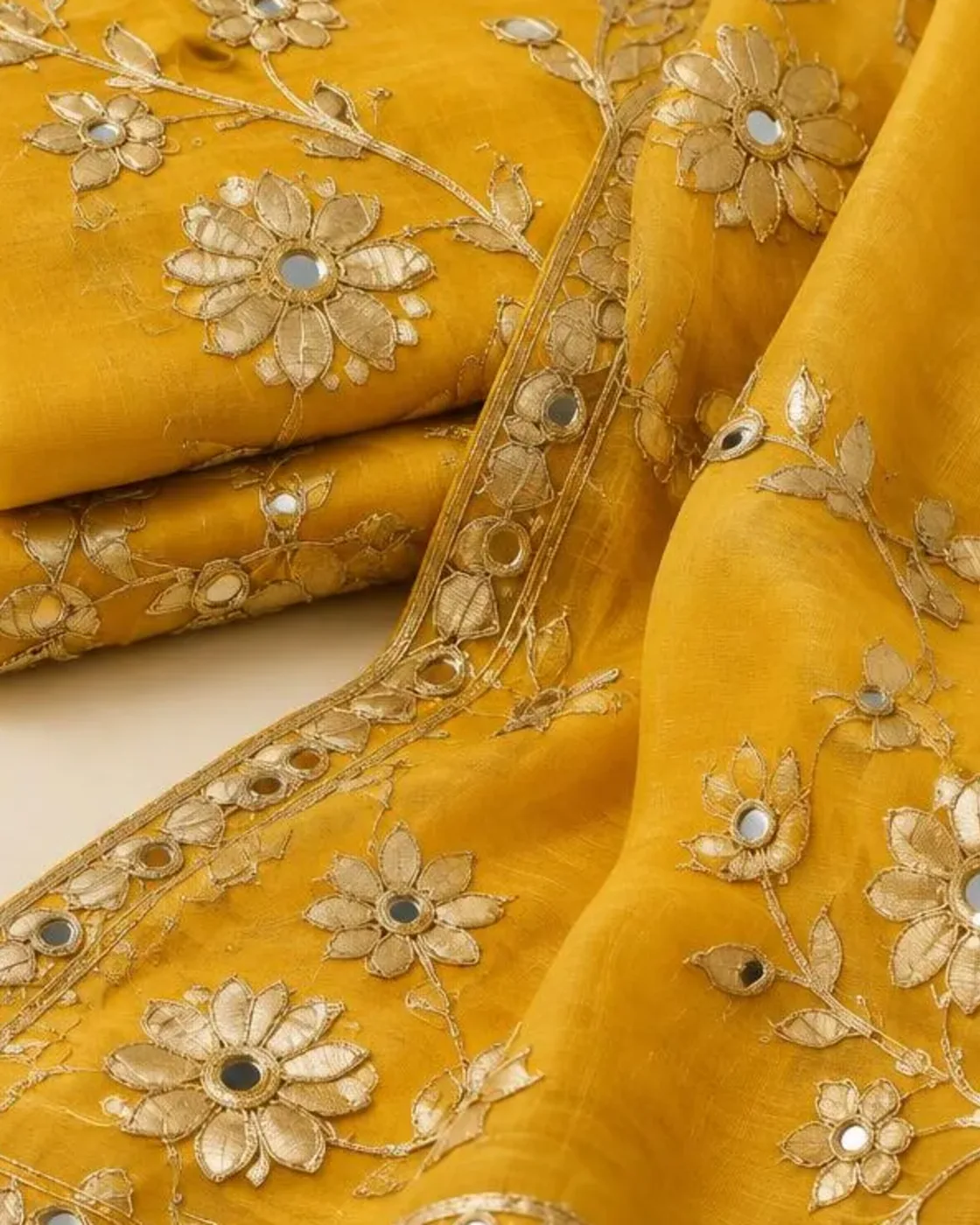Close-up of gold gota patti florals and mirrors on marigold chanderi