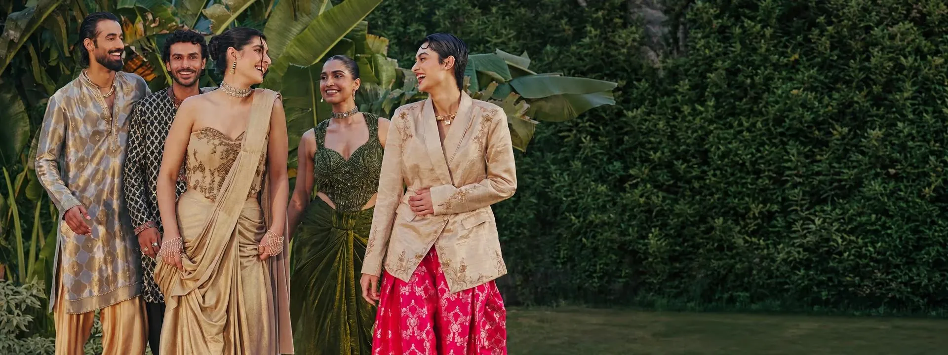 Festive campaign with models in metallic tissue and gold-toned outfits in a tropical garden